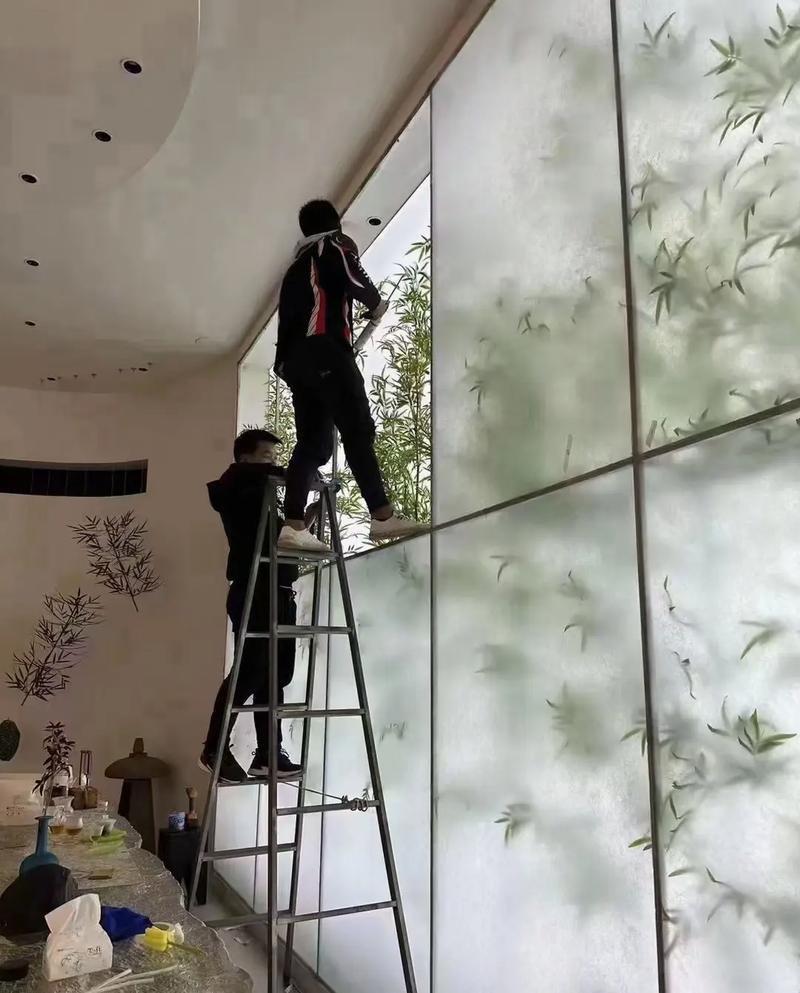 Installers fitting large printed acrylic wall panels from a ladder