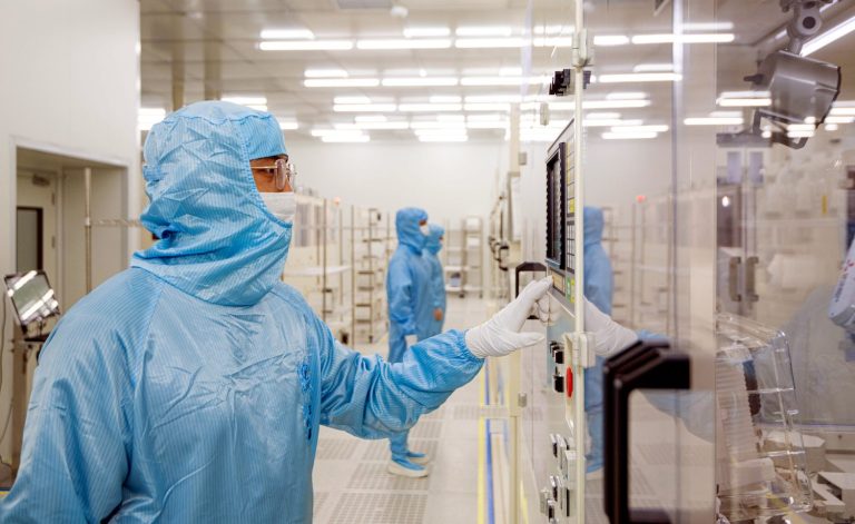 Technician inspecting clear acrylic panels in a cleanroom